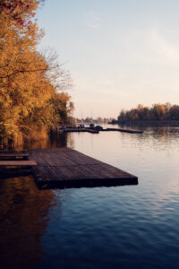 Abendsonnenuntergang an der Alten Donau Wien mit ruhigem Flusswasser, orangen Himmelspiegelungen und Uferlandschaft.