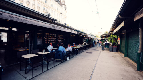 Outdoor seating at Naschmarkt beneath original Art Nouveau structures.