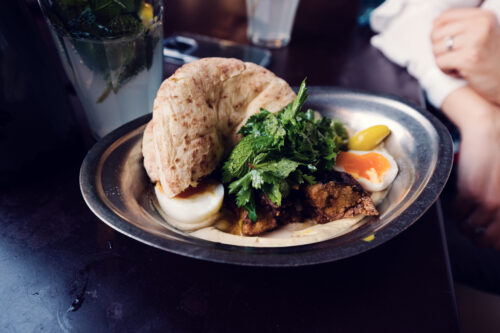 Colorful mezze at NENI with homemade hummus, egg, and fresh pita bread.