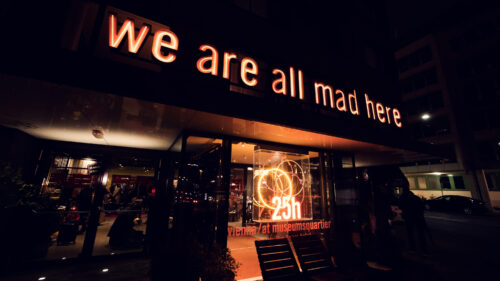Entrance of Ribelli with its glowing sign and warm lighting on a Vienna street.