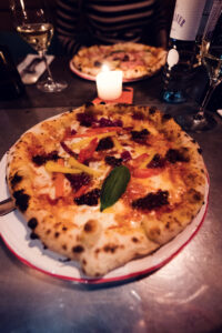 Detail of Ribelli's signature Neapolitan pizza with bubbling crust emerging from wood oven.