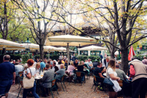 Bustling beer garden at Schweizerhaus, where vintage wooden tables sit beneath sprawling chestnut trees.