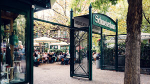 Green-shuttered entrance of Schweizerhaus framed by chestnut trees in the Prater.