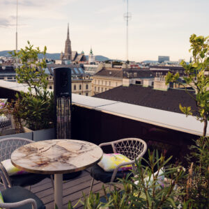 Espace lounge commun de l'Atmosphere Rooftop Bar avec des éléments de design viennois et vue sur les toits.