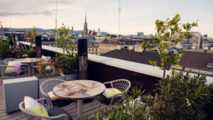 Espace lounge commun de l'Atmosphere Rooftop Bar avec des éléments de design viennois et vue sur les toits.