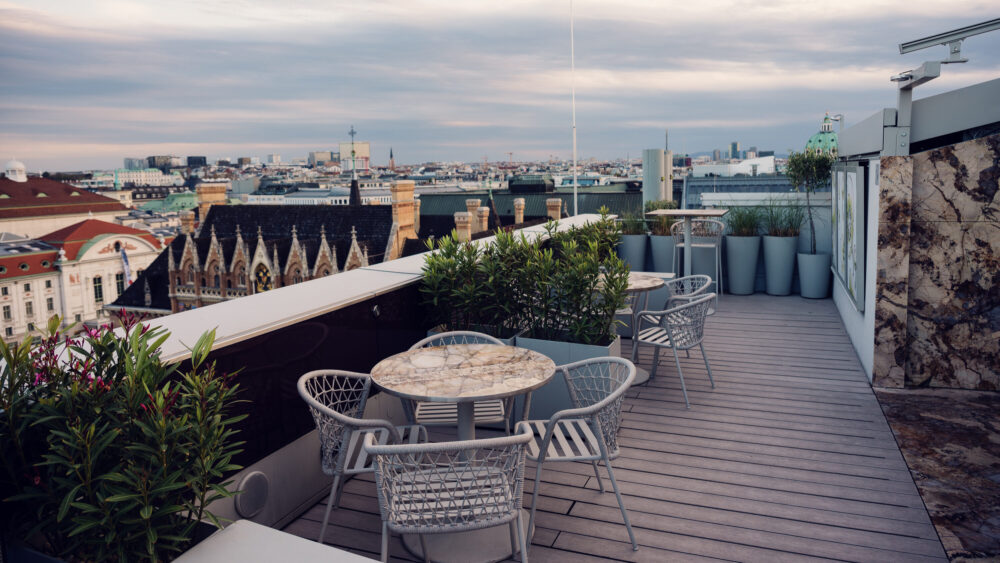 Plant-surrounded seating nooks at Atmosphere Rooftop Bar's terrace creating natural photo opportunities.