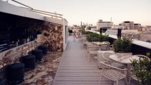Espace extérieur de l'Atmosphere Rooftop Bar avec tables et tabourets de bar face à la vue sur la ville.