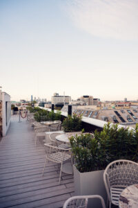 Salon extérieur de l'Atmosphere Rooftop Bar à Vienne avec mobilier en rotin rembourré et vue sur la ville.