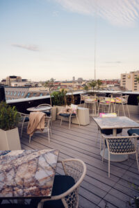 Terrasse extérieure de l'Atmosphere Rooftop Bar à Vienne pendant l'heure dorée, avec des sièges lounge.