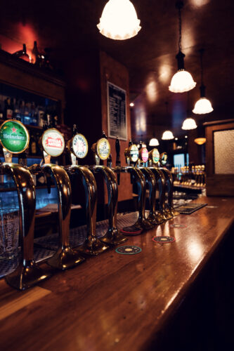 Evening atmosphere at Flanagan's draft beer station, where warm lighting illuminates row of traditional tap handles.