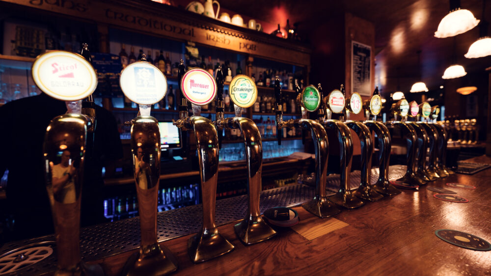 Traditional beer tap station at Flanagan's Irish Pub Vienna, where polished brass taps and iconic brand badges showcase authentic pub culture.
