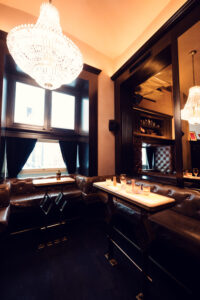 Main lounge area of Kleinod Vienna showing arrangement of velvet sofas and brass-trimmed cocktail tables.