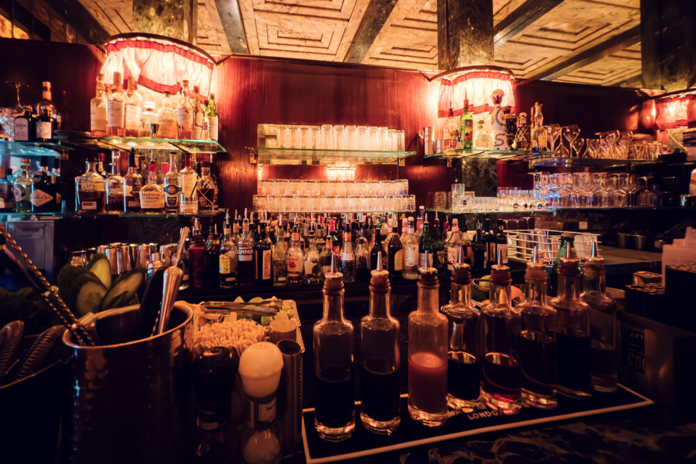 Premium spirits collection at Loos American Bar Vienna, where carefully curated bottles line historic shelves against original marble backdrop.
