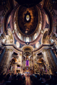 Innenraum der Peterskirche in Wien mit barockem Deckenfresko von Johann Michael Rottmayr, vergoldetem Stuck und natürlichem Licht auf dem Hauptaltar.