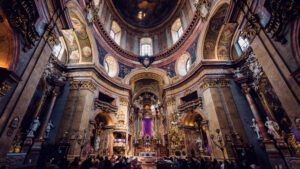 Richly decorated interior of St. Peter's Church Vienna (Peterskirche) featuring elaborate marble columns, intricate pulpit carvings, and the famous oval-shaped floor plan characteristic of Baroque church architecture.