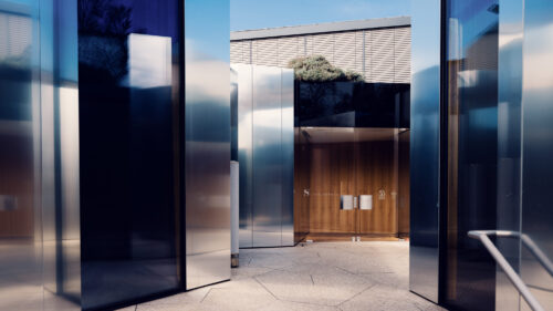 Entrance of Steirereck restaurant with mirrored glass panels and wooden door.