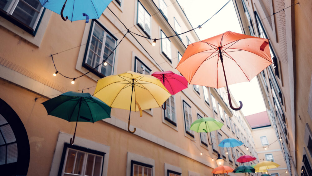 Detail of suspended umbrellas against historic architecture at Sünnhof passage.