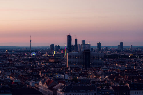 Golden hour sunset view from Aurora Rooftop Bar Vienna Austria, panoramic evening cityscape with warm lighting illuminating Vienna's architectural features.