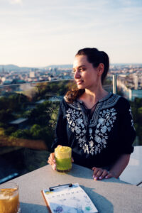 Adriana disfrutando de un cóctel en la Aurora Rooftop Bar de Viena con vistas panorámicas sobre la ciudad.