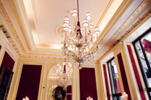 Detailed view of the ornate ceiling in Café Sacher Vienna with stucco decorations and historic lighting.