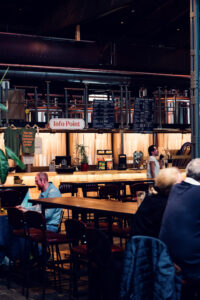 Long wooden communal tables inside Gleis//Garten Vienna with food stalls in the background.