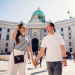 Adriana and Mario walking together at Michaelerplatz Vienna with the ornate Baroque facade of the Hofburg Palace.