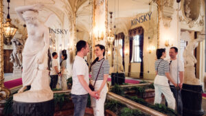 Adriana et Mario devant l'angle baroque du Palais Kinsky à Vienne avec stucs élaborés et détails architecturaux classiques.