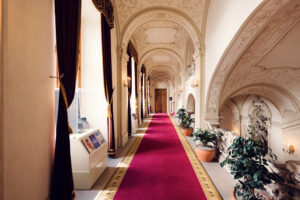 Couloir baroque du Palais Kinsky à Vienne avec colonnes de marbre, arcs classiques et décorations ornementales.