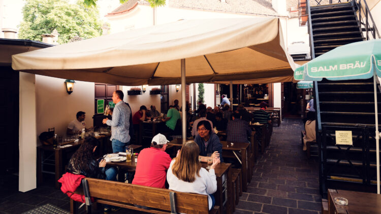 Outdoor terrace with wooden tables and benches at Salm Bräu.