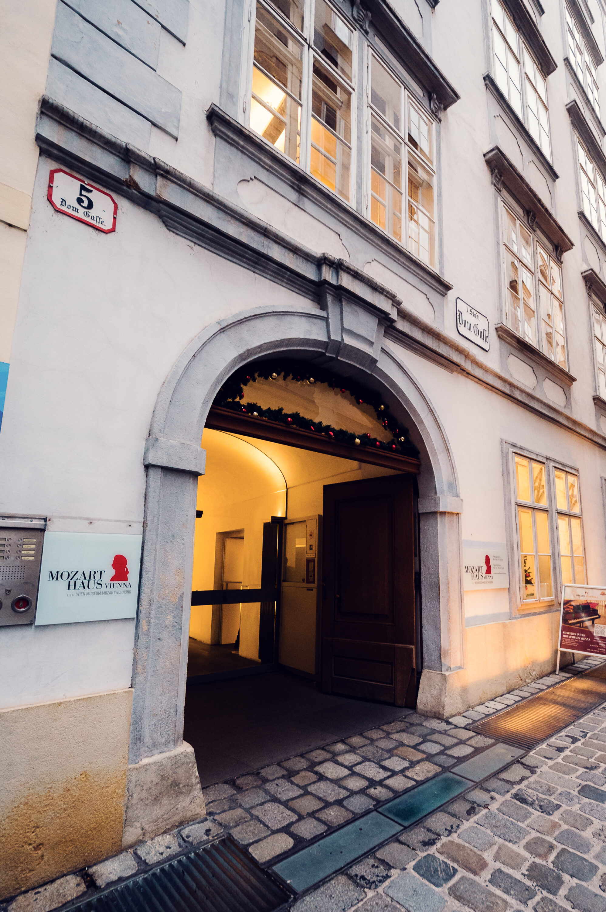 Arched entrance to Mozarthaus Vienna on Domgasse street in the evening.