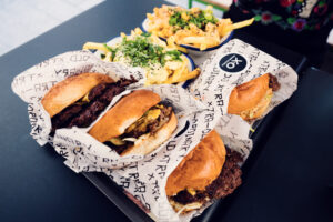 Burger de bœuf avec frites au XO Grill Neubaugasse, servi sur une planche en bois.
