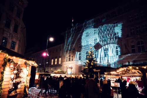 Festive light decorations at Altwiener Christkindlmarkt with historic architecture backdrop.