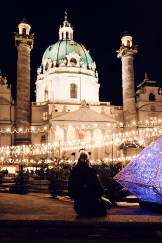 Festive lights and decorations at Art Advent on Karlsplatz with Baroque church architecture in background.