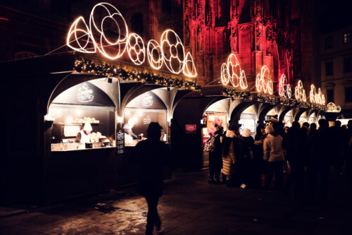 Visitors browsing Christmas market stalls on Stephansplatz in front of St. Stephen's Cathedral (Stephansdom), Vienna.