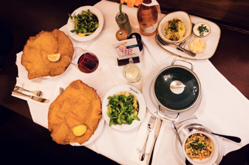 Wiener Schnitzel grande quanto un piatto e specialità Tafelspitz al ristorante Figlmüller con contorni tradizionali.