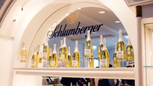 Schlumberger sparkling wine bottles displayed beneath an arched window with the Schlumberger logo in the visitor shop.