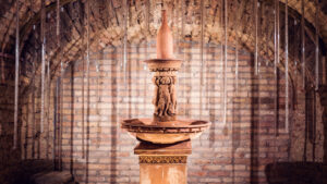 Ornamental fountain sculpture topped with a bottle shape in a brick-vaulted chamber of the Schlumberger cellars.