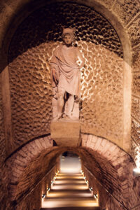Classical statue of Bacchus in a stone niche above an illuminated stairway inside the Schlumberger cellars.