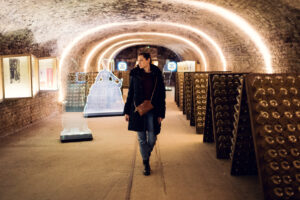 Adriana walking through the vaulted exhibition cellar past riddling racks and displays at Schlumberger Kellerwelten.