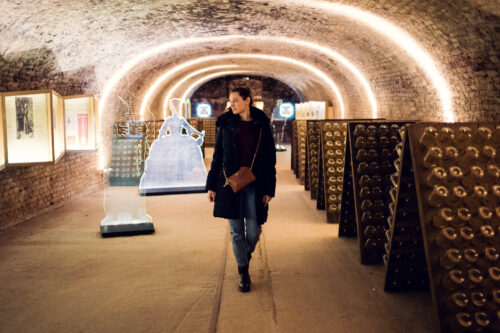 Adriana walking through the vaulted exhibition cellar past riddling racks and displays at Schlumberger Kellerwelten.