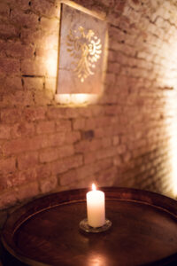 Candlelit wine barrel with an illuminated double-headed eagle crest on the brick wall in the Schlumberger cellars.