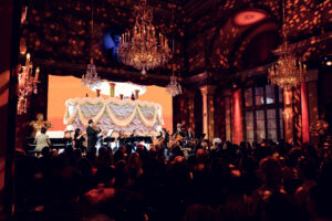 Live orchestra and soprano on stage with draped LED screen in the Strauss Hall.