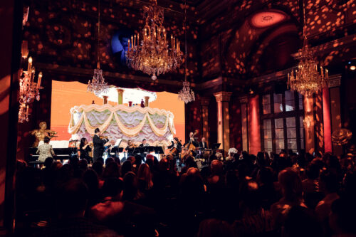 Live orchestra and soprano on stage with draped LED screen in the Strauss Hall.