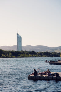Bagnanti si rilassano su una piattaforma di balneazione galleggiante sul Nuovo Danubio, sotto il Millennium Tower.