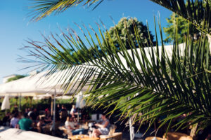 Foglie di palma incorniciano un'affollata terrazza di un bar di Copa Beach in un pomeriggio di sole.