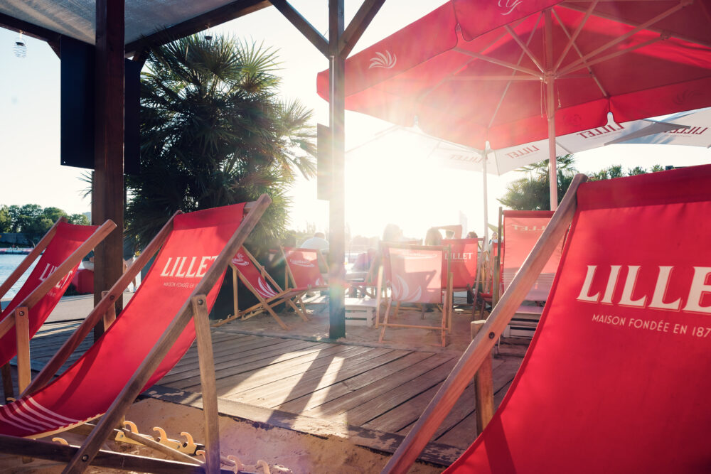 Red deck chairs and parasols on a sunlit Copa Beach terrace.