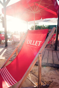 Una sdraio rossa sotto un ombrellone sulla sabbia di Copa Beach al tramonto.