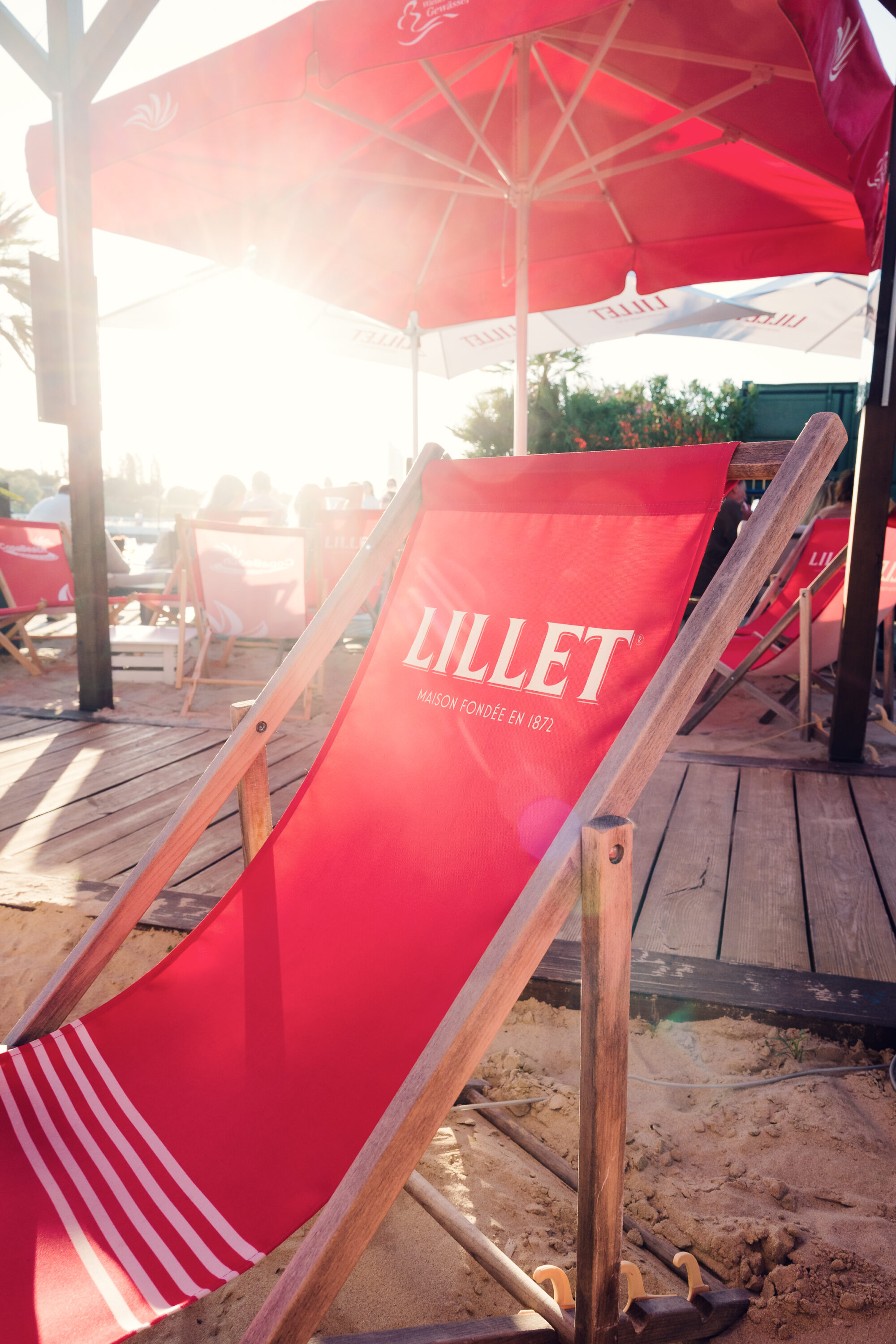 Una sdraio rossa sotto un ombrellone sulla sabbia di Copa Beach al tramonto.