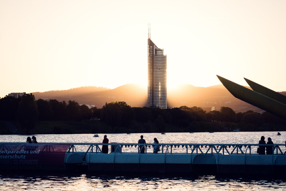 Visitatori sul ponte galleggiante al tramonto, con il Millennium Tower oltre Copa Beach.