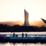 Besucher auf der schwimmenden Brücke bei Sonnenuntergang, dahinter der Millennium Tower hinter Copa Beach.